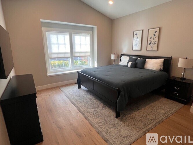 A bedroom with a large bed, a window, and a wooden floor.