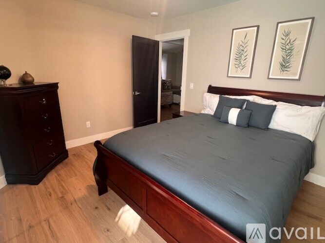 A bedroom with a black bed and a wooden dresser.