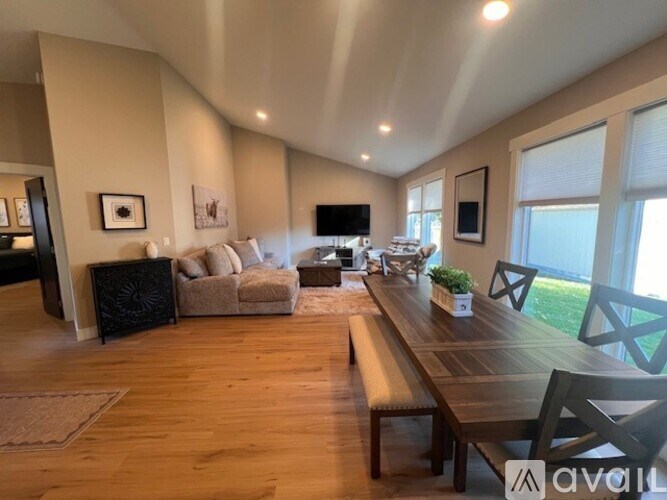A bathroom with a tub, sink, mirror, and wooden floors.