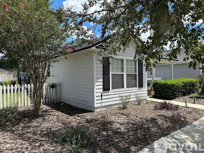A small white house with a tree in front of it.