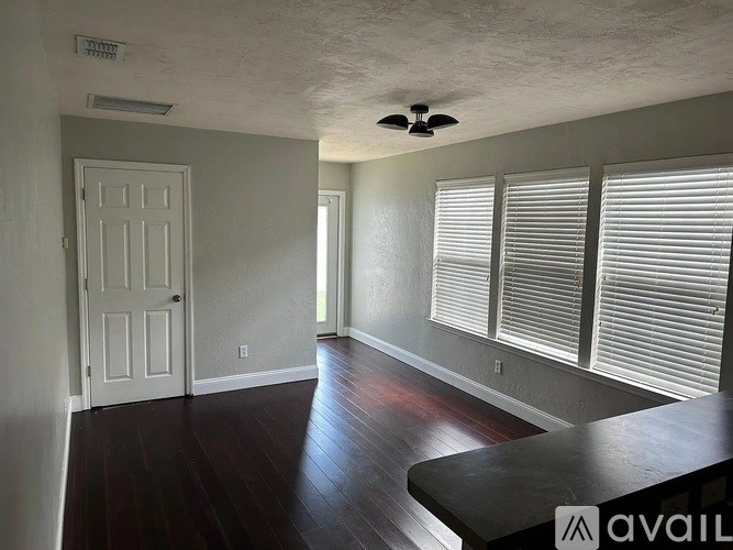 A room with a white door, a window with blinds, and a ceiling fan.