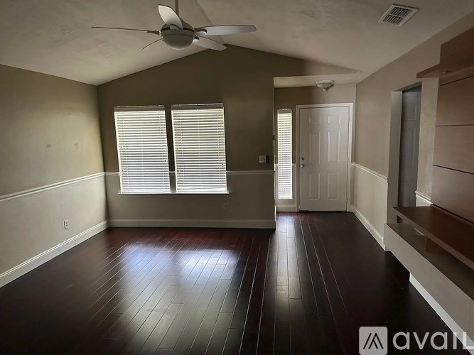 A room with a ceiling fan and wooden flooring.