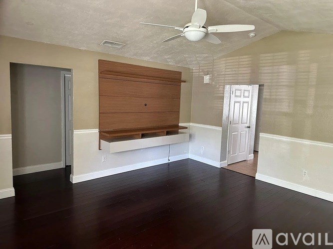 A room with a ceiling fan and a wooden door.