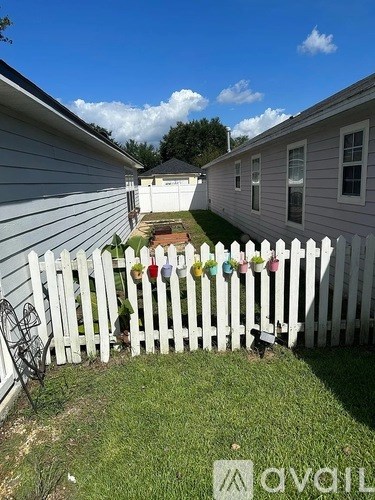 A white picket fence with a chair and a table in front of a house.