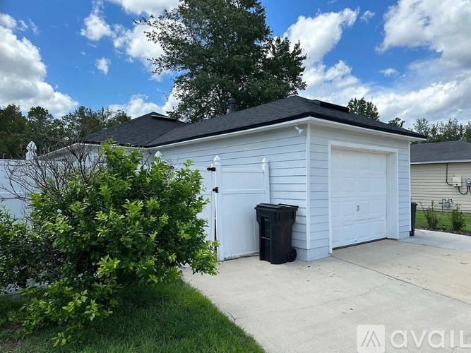 A two-car garage with a black trash can in front.