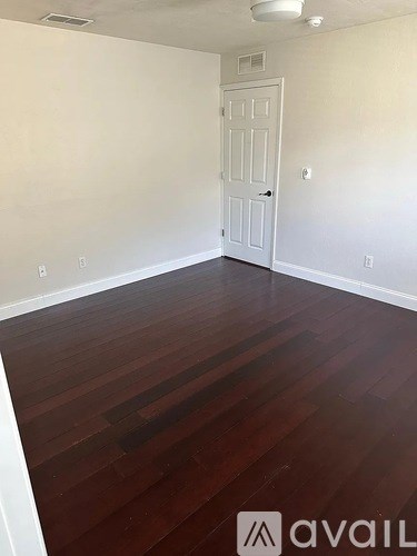A room with a white door and wooden flooring.
