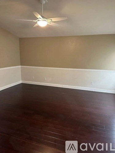 A room with a ceiling fan and wooden flooring.