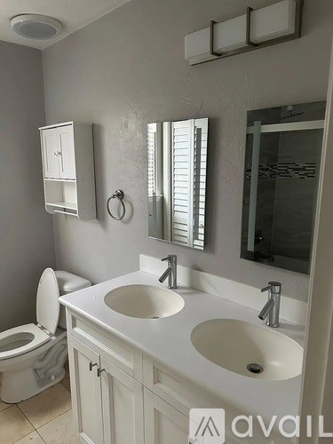 A bathroom with a toilet, sink, and mirror.