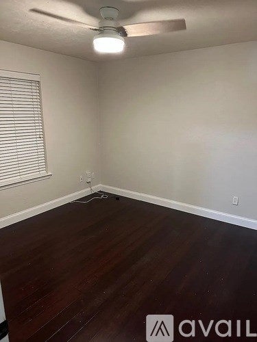 A room with a ceiling fan and wooden flooring.