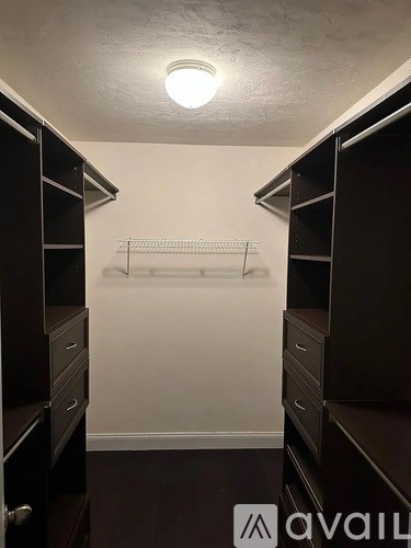 A walk-in closet with a white wall and a light on the ceiling.
