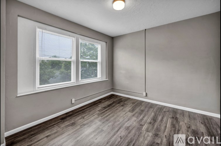 A room with wooden flooring and a window with blinds.
