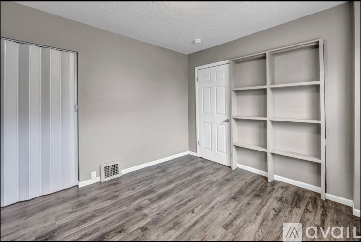 A room with a wooden floor and a built-in shelf unit.