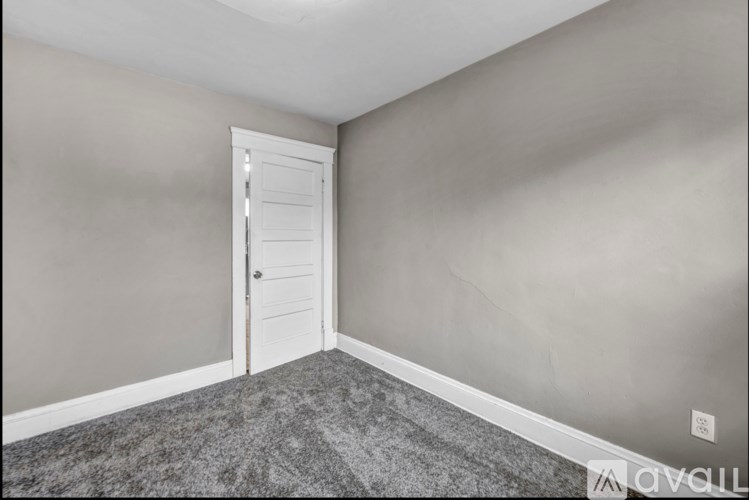 A room with a white door and grey carpet.