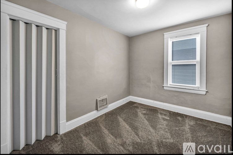 A room with a window and a carpeted floor.