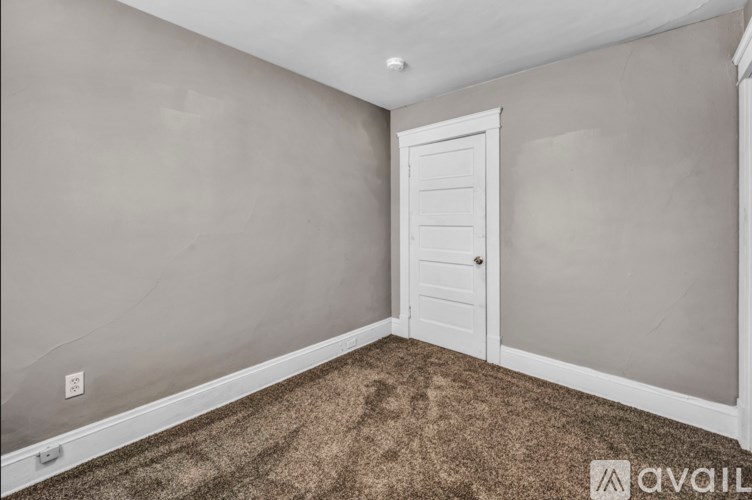 A room with a carpeted floor and a white door.