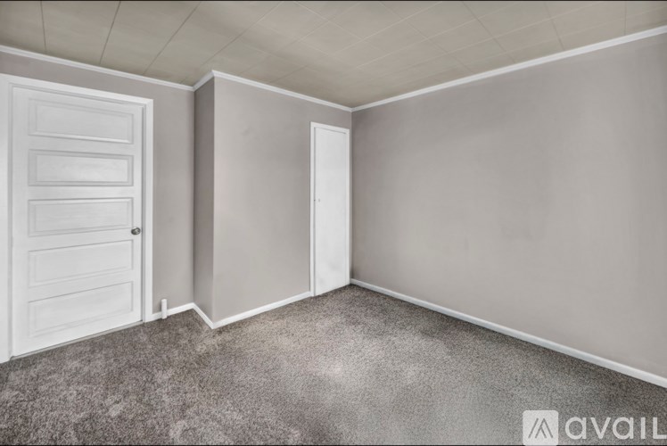 A room with a carpeted floor and a white door.