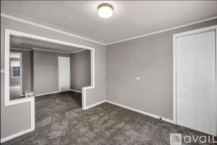 A spacious room with grey carpeting and white walls.