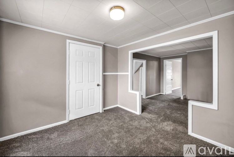 A room with a white door and carpeted floor.