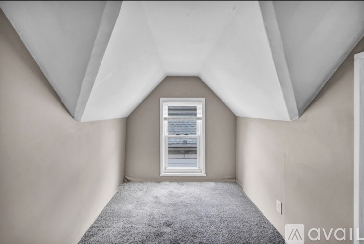 A room with a window and a carpeted floor.