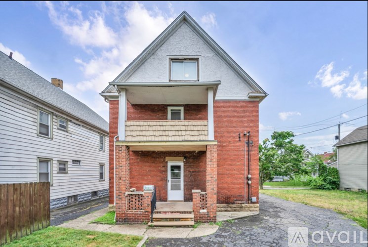 A two-story house with a red brick exterior and a white door is for sale.