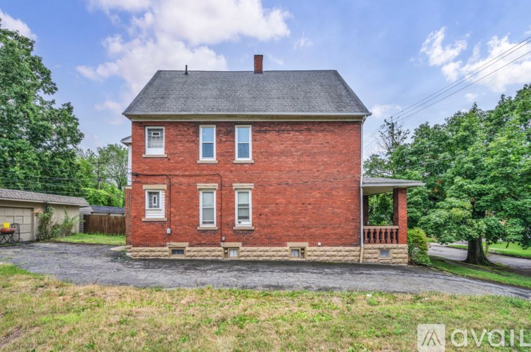 A red brick house with a black roof and a chimney.