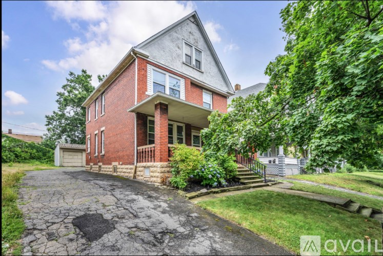 A red brick house with a driveway in front.