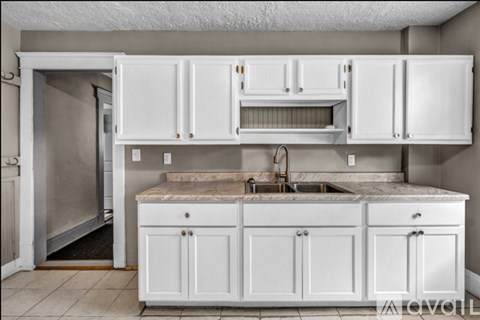 A kitchen with white cabinets and a marble countertop.