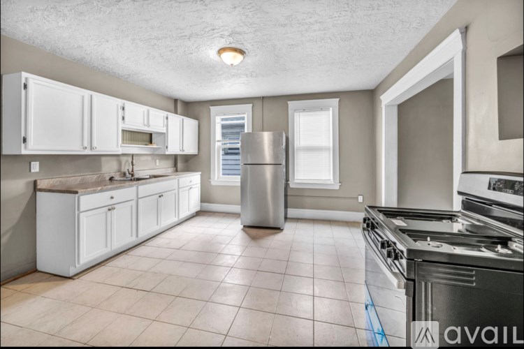 A kitchen with white cabinets and a stainless steel refrigerator.