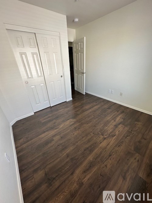 A room with white walls and wood flooring with two white doors.