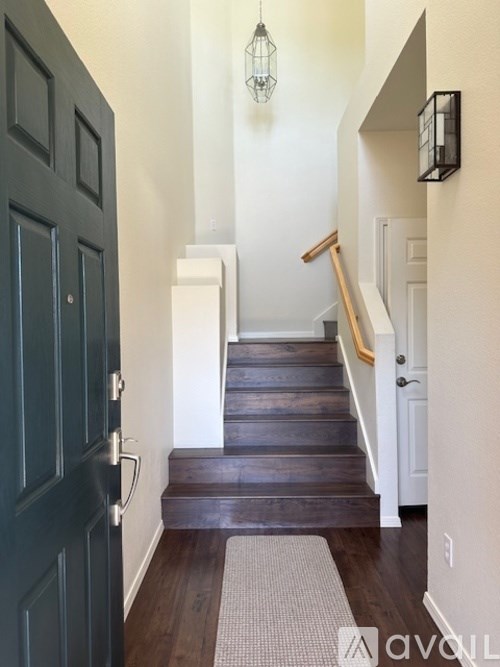 A hallway with a dark green door and a light brown carpet.