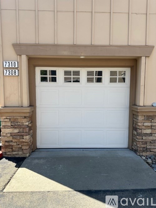 A white garage door with a brick pillar on each side.