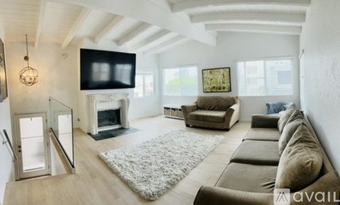 A living room with a grey couch and a television on the wall.