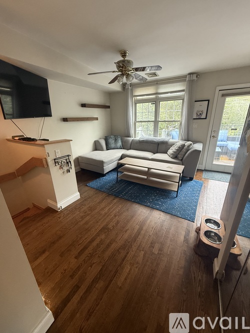 A living room with a couch, a television, and a ceiling fan.
