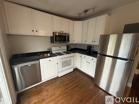 A kitchen with white cabinets and a stainless steel refrigerator.