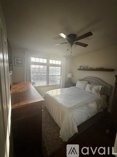 A bedroom with a bed, dresser, and window.