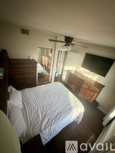 A bedroom with a bed, dresser, and a ceiling fan.