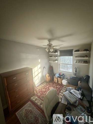 A room with a ceiling fan and a rug on the floor.