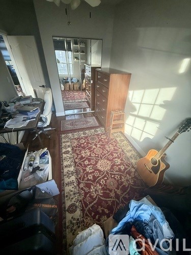 A room with a guitar and a rug on the floor.