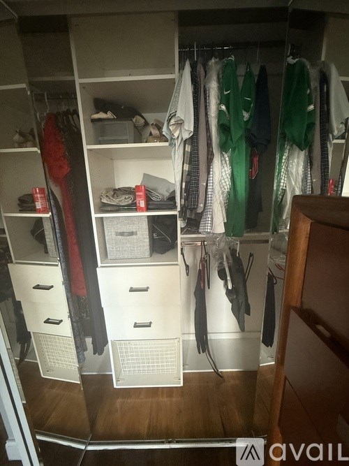 A white closet with clothes hanging and drawers underneath.