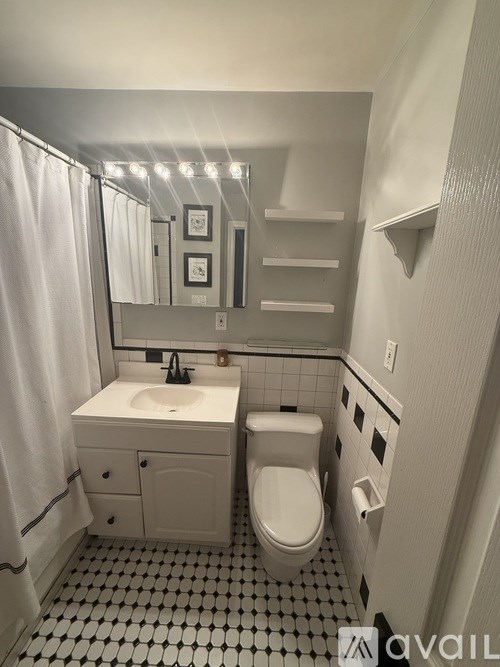 A bathroom with a toilet, sink, and mirror.