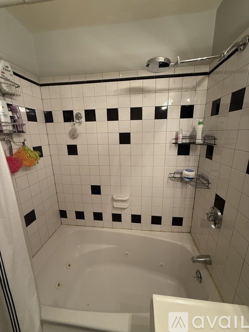 A bathroom with a white tub and black and white tiles.