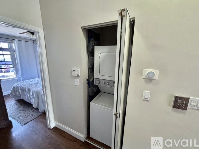 A white wall with a small fridge in a bedroom.