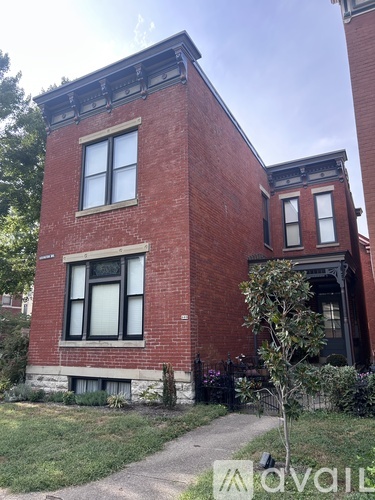 A red brick house with a tree in front.