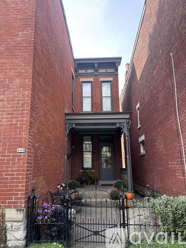 A black gate leads to a brick building with a balcony.