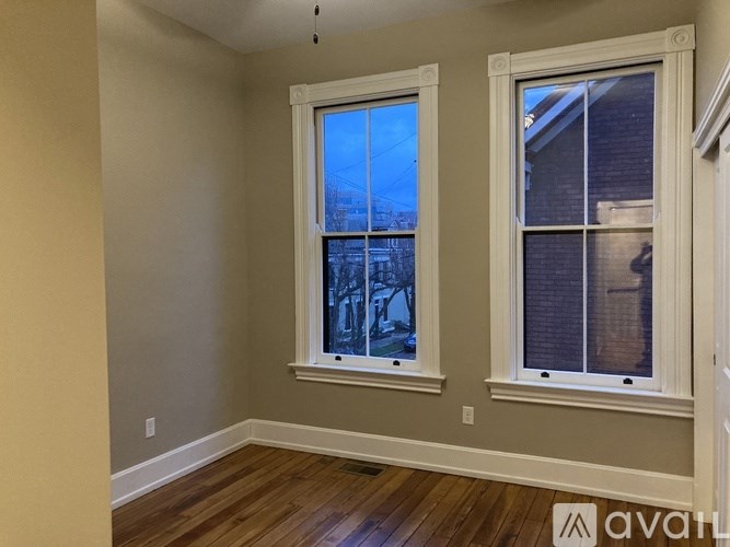 A room with two windows and wooden floors.