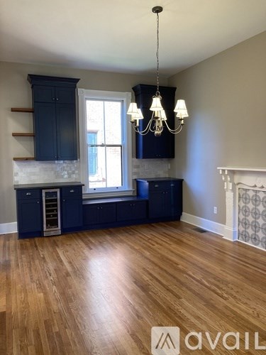 A kitchen with dark blue cabinets and a wooden floor.