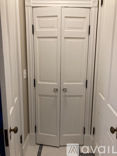 A white double door with a black handle and a small square window above the door.
