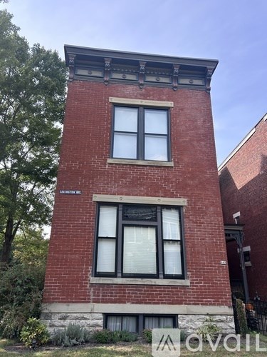 A red brick building with a black window and a sign that says "AVAIL".