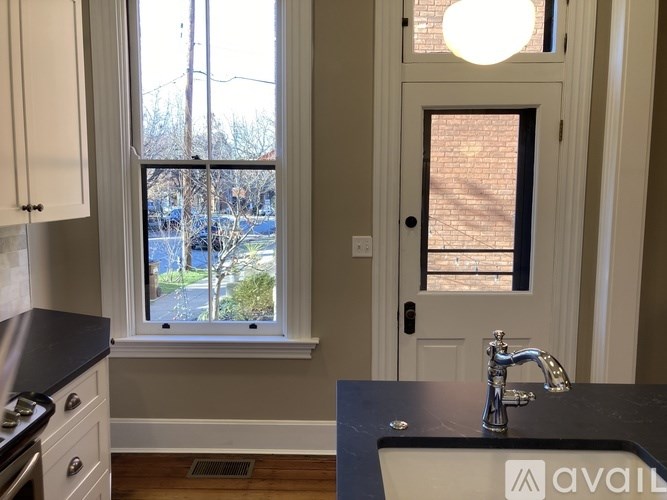 A kitchen with a black countertop and a window with a view of the outside.