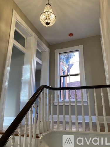 A white staircase with a chandelier hanging from the ceiling.